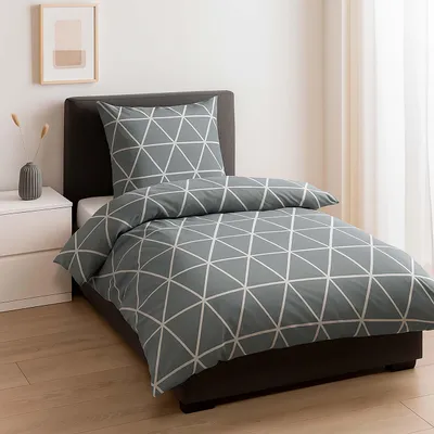 A neatly made bed with a geometric pattern duvet cover and pillow in a bedroom setting.