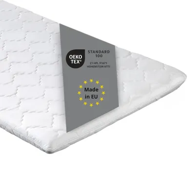 A close-up, angled view of a white mattress topper with a grey label indicating certifications and origin.
