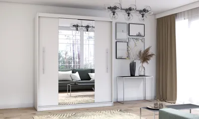 A white sliding door wardrobe with mirrored doors is shown in a well-lit room with a sofa reflected in the mirror.