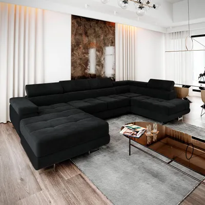 A modern living room scene with a large, black sectional sofa and a glass coffee table.