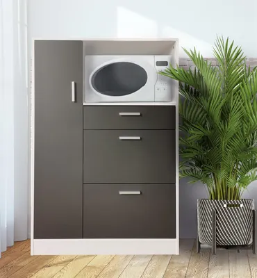 A kitchen cabinet with a microwave and drawers, next to a potted plant.