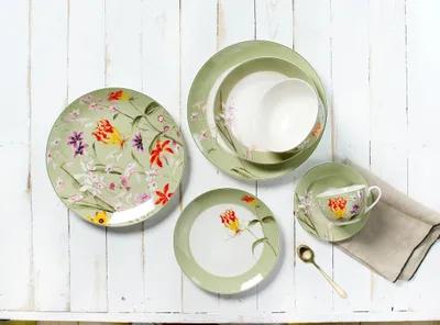A set of floral-patterned tableware is arranged on a white wooden surface.