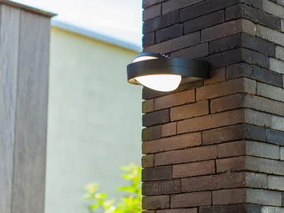 An outdoor wall light is mounted on a brick pillar.
