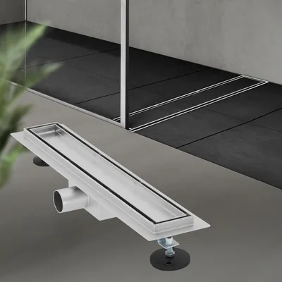 A linear shower drain is shown in the foreground, with a tiled shower area in the background.