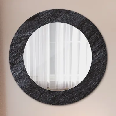 A round mirror with a textured black frame hangs on a light-colored wall.