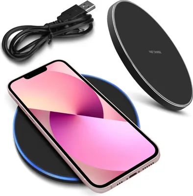 A smartphone is placed on a wireless charger, with a USB cable in the background.