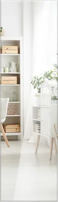 A bright, minimalist room with a white bookshelf and a white cabinet with wooden legs.