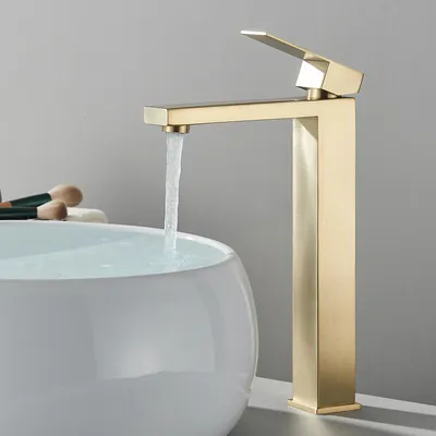 A modern gold faucet is running water into a white basin.