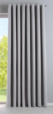 A gray curtain hanging in front of a window with green trees visible outside.