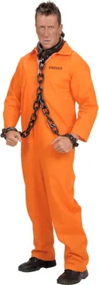 A man dressed as a prisoner in an orange jumpsuit with chains around his neck and wrists, standing against a white background.