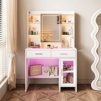 A white vanity table with a lighted mirror, drawers, and shelves, displaying makeup and bags.
