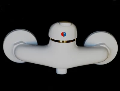 A white and gold shower faucet against a black background.