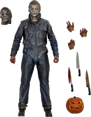 A collection of action figures and accessories, including a main figure, alternate heads, hands, knives, and a pumpkin.
