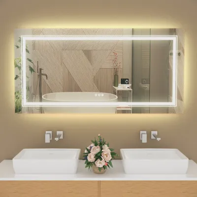 A modern bathroom vanity with two sinks, a large illuminated mirror, and a floral arrangement.