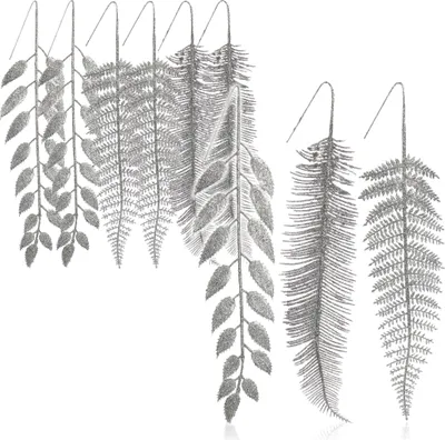 A collection of artificial silver glitter branches with different leaf shapes, arranged against a white background.
