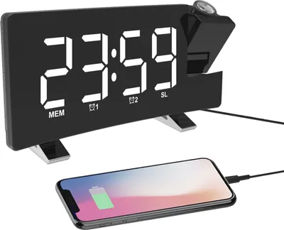 A digital alarm clock with a projection feature is shown, with a smartphone charging wirelessly on a surface below it.