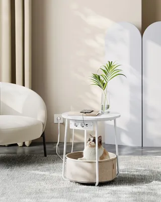 A cat sits in a round basket under a small round white table with integrated power outlets.