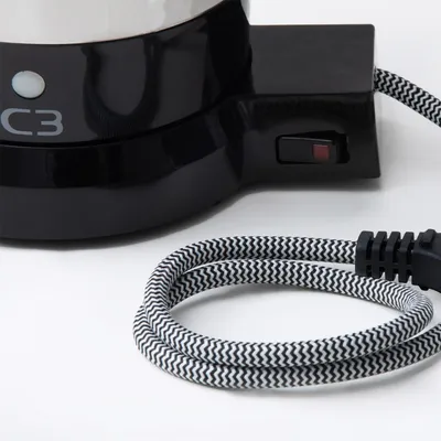 A close-up view of the base of a black coffee maker with a power cord coiled in the foreground.
