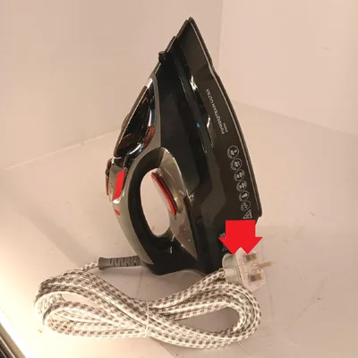 A black and red iron with its power cord and plug.