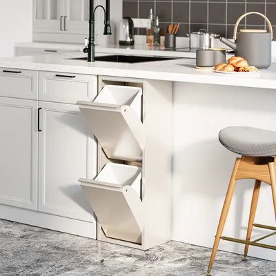 A modern kitchen with white cabinets and a white countertop. A pull-out trash bin system with two compartments is visible, along with a black faucet and sink.