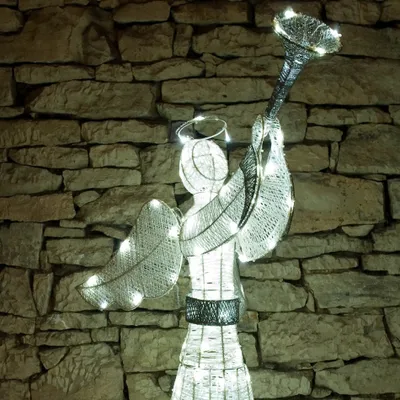 A lighted angel decoration against a stone wall.