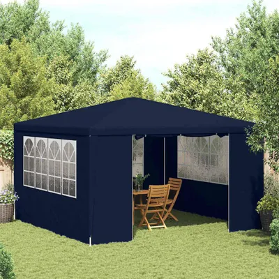 A navy blue party tent set up in a backyard with a wooden table and chairs inside.