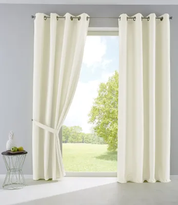 A pair of cream-colored curtains are shown hanging in front of a window with a view of a green field and trees.