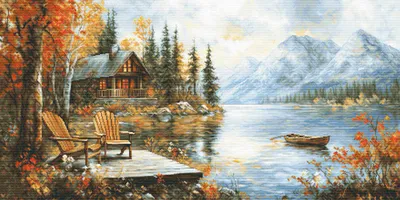 A serene lake scene with a cabin and mountains in the background, set during autumn.