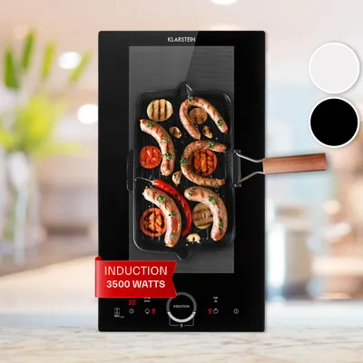 A close-up shot of a black induction cooker with a grill pan of sausages and vegetables on it.