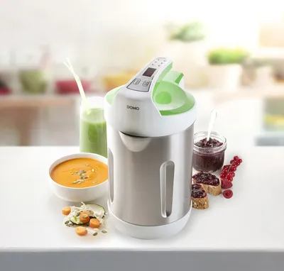 A soup maker is shown on a table with prepared food items like soup, jam on toast, and a smoothie.