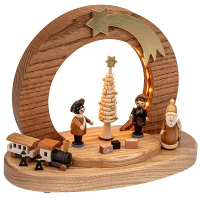 Erzgebirgische Holzkunst: Hölzerner LED-Sockel 'Bescherung' mit großem Holzbogen, Weihnachtsbaum in der Mitte und geschnitzten Holzfiguren rundum. Warmweiße LED-Beleuchtung, natur- und brauntöne.