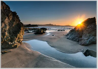 Produktbild von Wallario Wandbild Sonnenuntergang hinter einem Felsen am Strand, Größe: 70,30 x 100,30 cm, Poster mit weißem Kunststoffrahmen