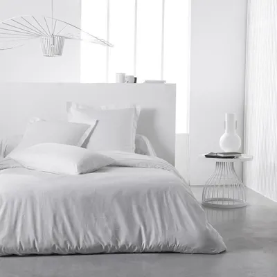 A white duvet cover is laid out on a bed in a minimalist bedroom setting.