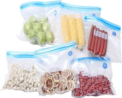 A collection of vacuum-sealed bags containing various food items, including grapes, corn on the cob, sausages, pistachios, dried lemon slices, and red beans, arranged on a white background.