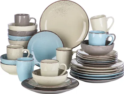 A collection of ceramic dinnerware, including plates, bowls, and mugs, arranged in stacks and groups.