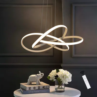 A modern LED pendant light hangs above a table with decorative items.