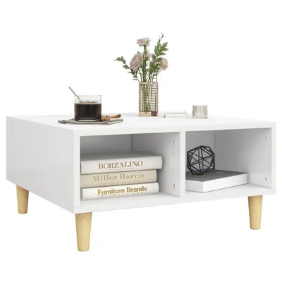 A white coffee table with wooden legs, decorated with a vase of flowers, a glass of coffee, and books.