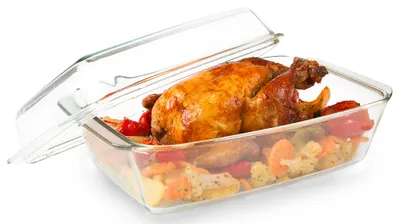 A roasted chicken with vegetables in a glass baking dish with the lid ajar.