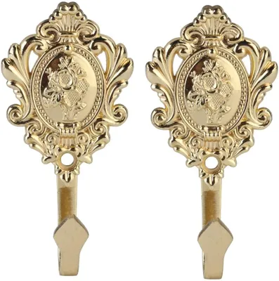 Two ornate gold curtain tie-back hooks.