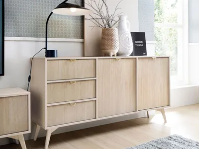 A modern sideboard with drawers and doors, decorated with a lamp and vases.