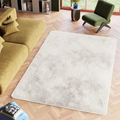 A modern living room with a yellow sofa, a green armchair, and a white rug.