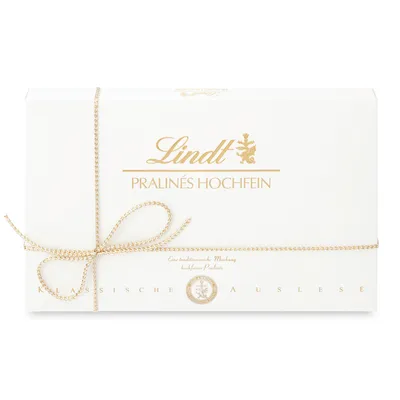 A white box of Lindt Pralines Hochfein, tied with a gold ribbon and bow.