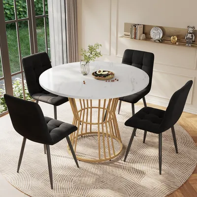 A round dining table with four black chairs set up in a dining area with natural light coming from a large window.