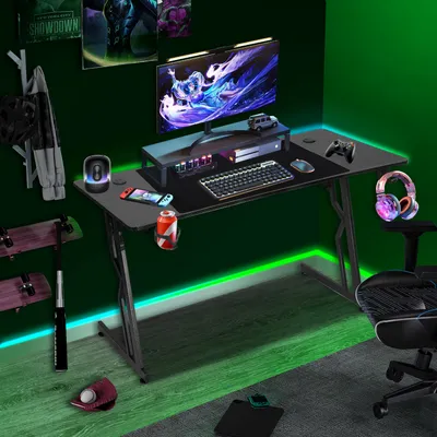 A gaming desk setup in a room with green ambient lighting.