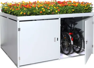 A white metal bicycle garage with a planter box filled with colorful flowers on top. One door is open, revealing two bicycles inside.