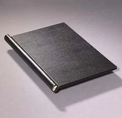 A black binder is shown lying on a light gray surface, casting a shadow.