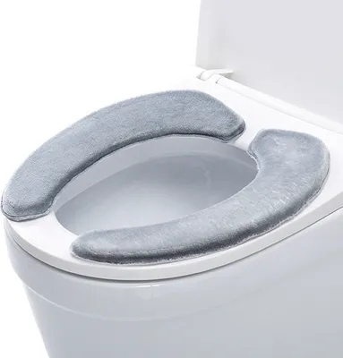 A close-up view of a toilet seat with two gray plush toilet seat covers placed on it.