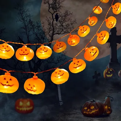 A Halloween-themed scene with strings of illuminated pumpkin-shaped lights against a dark, spooky background with a large moon, bare trees, and a graveyard.