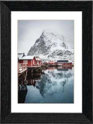 A framed picture of red houses on stilts in a snowy landscape.