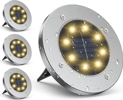 A set of four solar-powered ground lights, with one light prominently displayed in the foreground and three others arranged behind it.